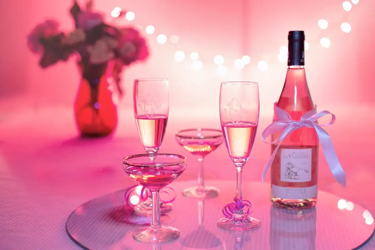 Pahare de vin roz și o sticlă pe o masă festivă, într-o atmosferă de sărbătoare