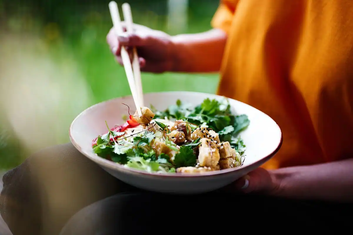 Bol cu salată proaspătă și tofu, mâncat cu bețișoare, gustare ușoară pentru dinți
