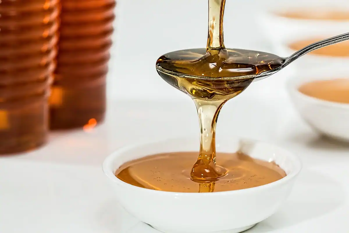 Miere aurie care se scurge dintr-o lingură, un îndulcitor natural