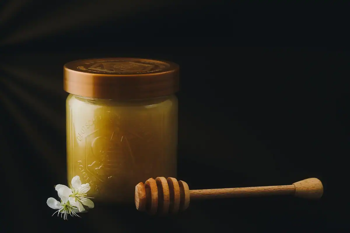 Borcan de sticlă cu miere de floare și o lingură specială pentru miere