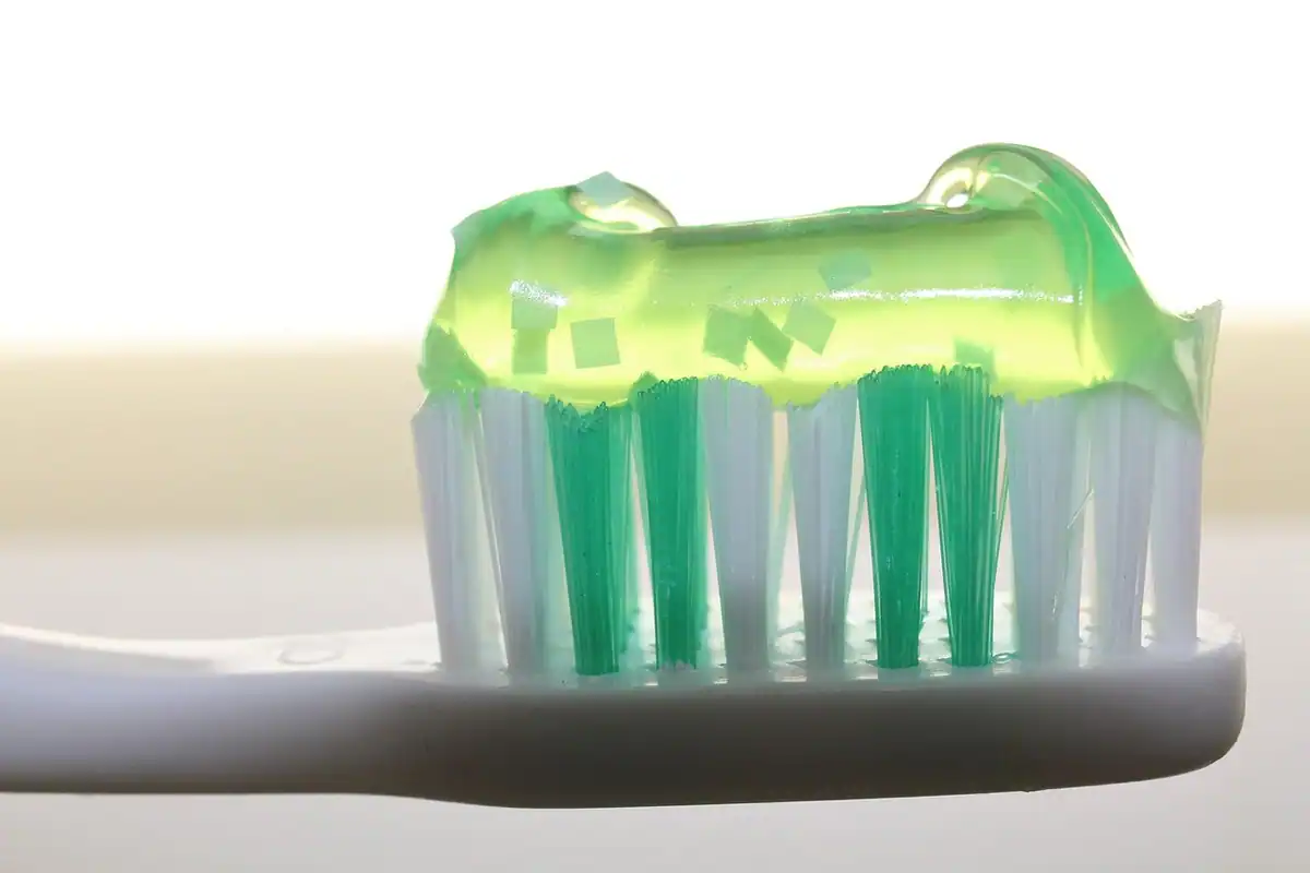 Periuță cu pastă de dinți verde, sub formă de gel, pe fundal luminos